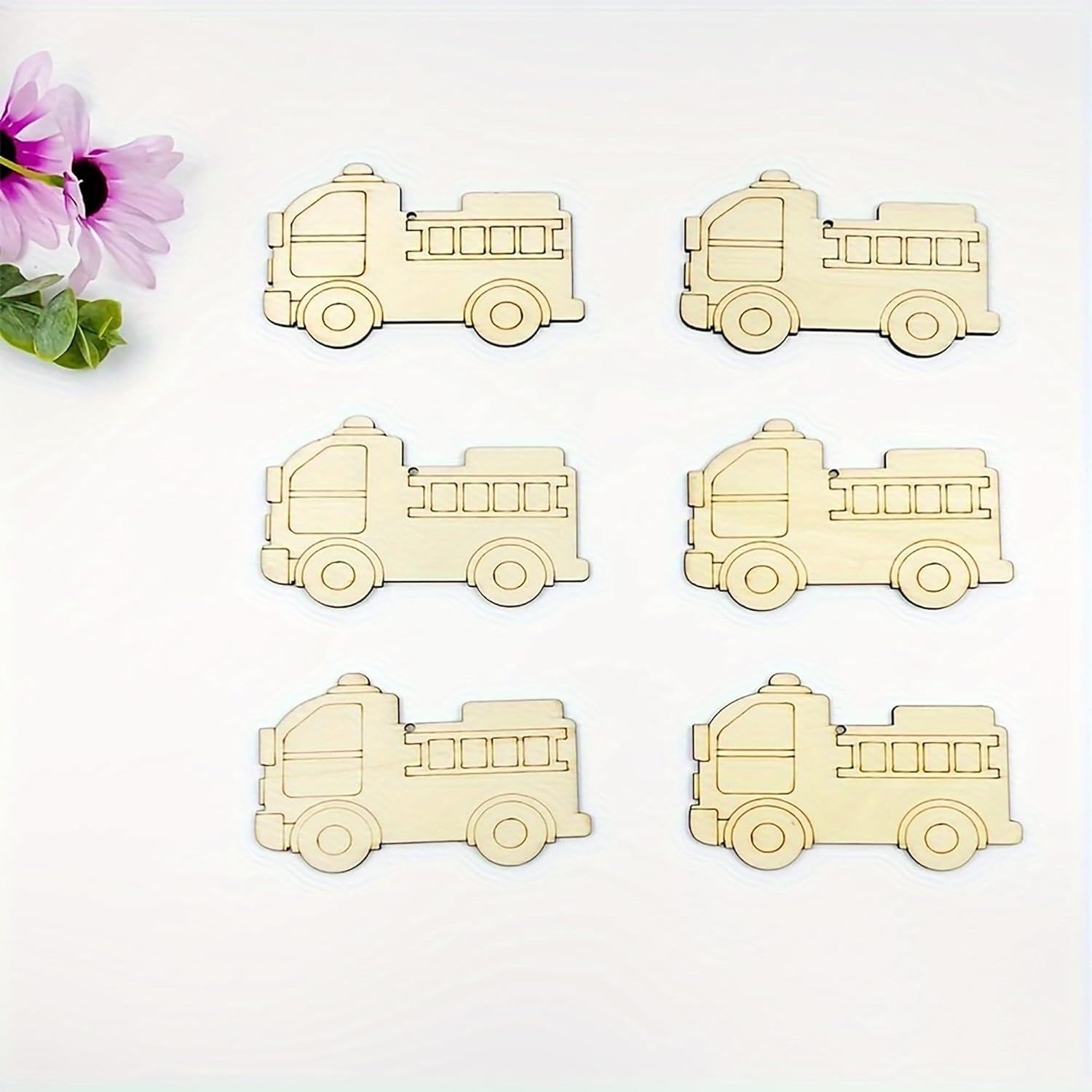 Six wooden fire truck toys on a white background with a pink flower.