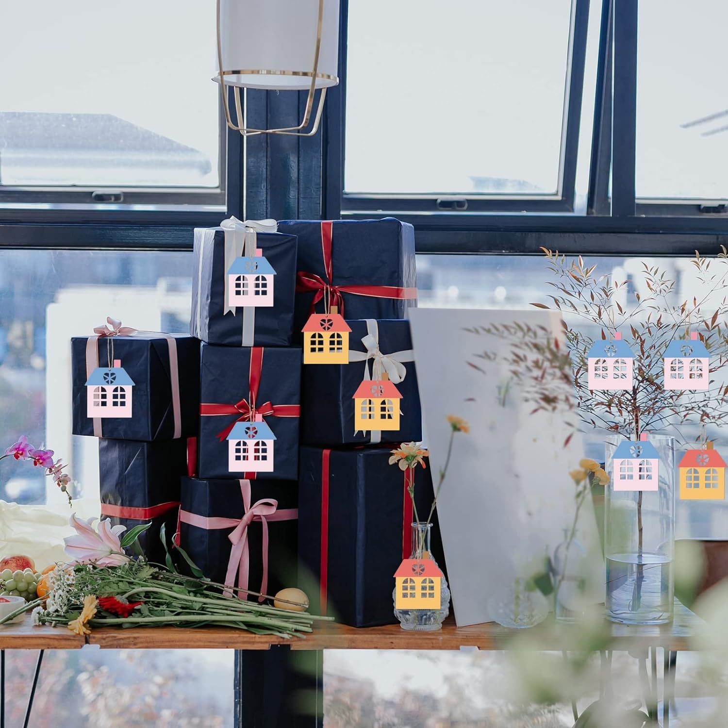 Stack of gift boxes with decorative house tags on a table by a window