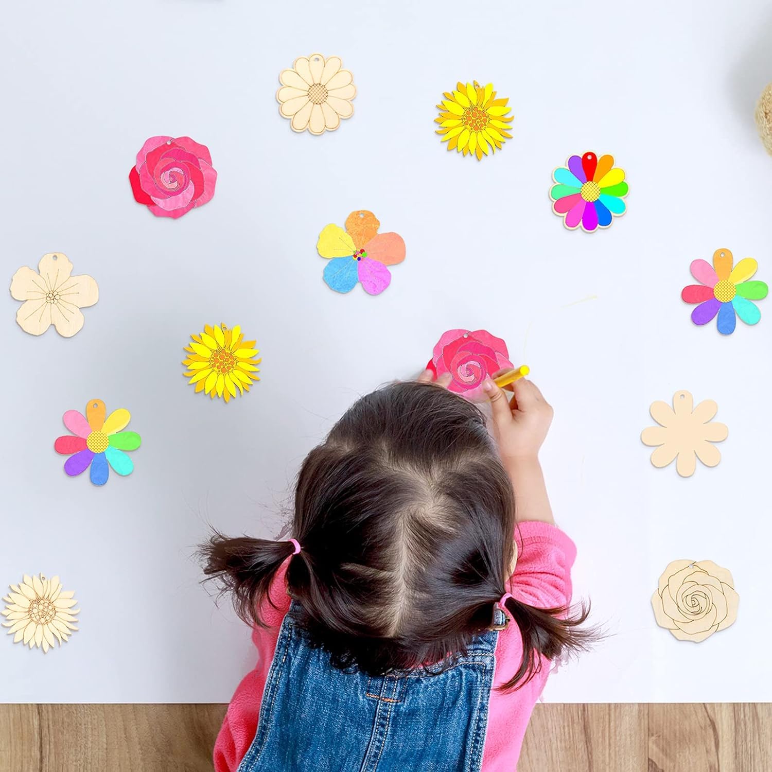 Child painting a flower on a wall with colorful flower decals.