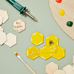 Hexagonal wooden tiles with bee designs and 'Bee Happy' sign on a light green background