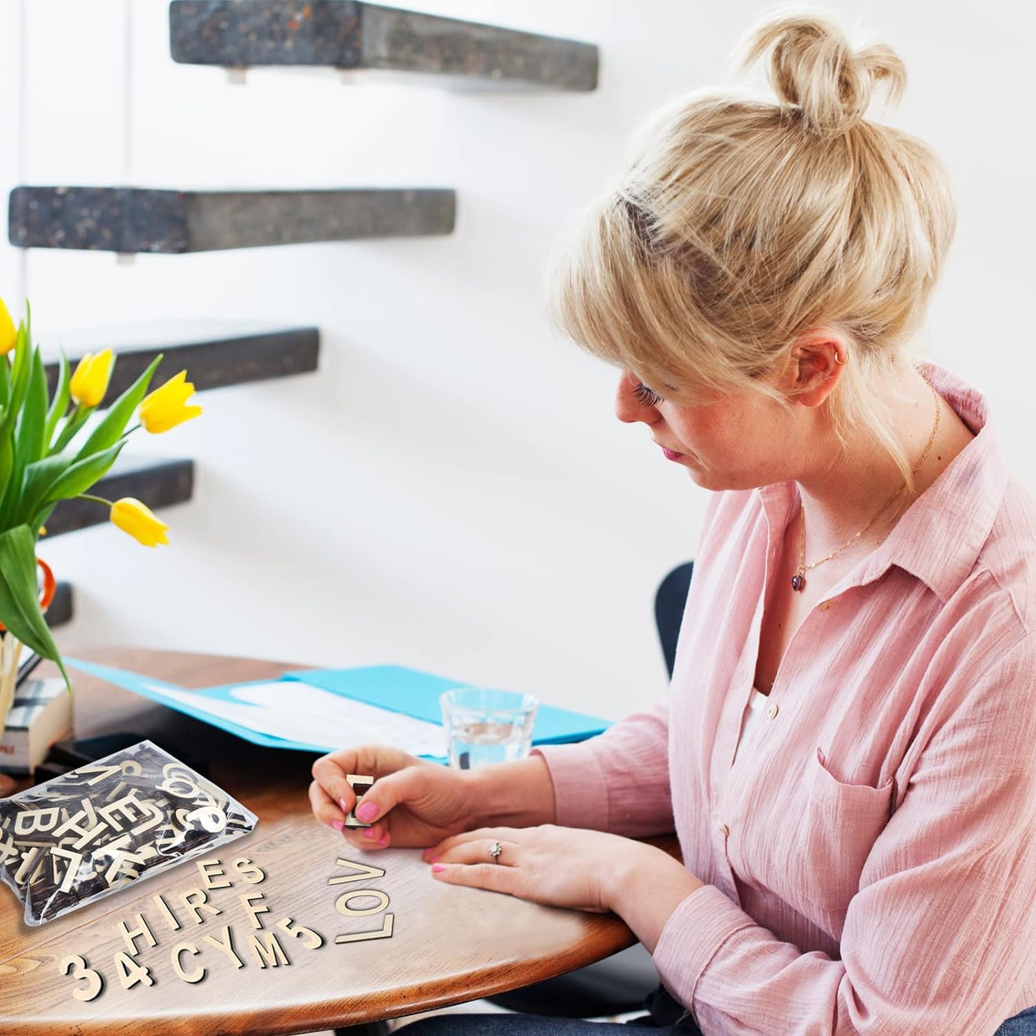 Woman arranging letters on a table with a decorative wall in the background