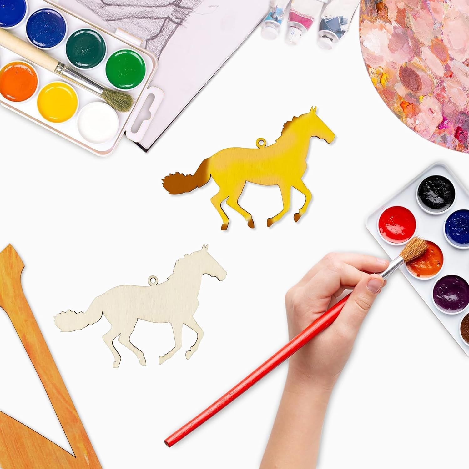 Coloring horse-shaped objects with watercolors on a white surface