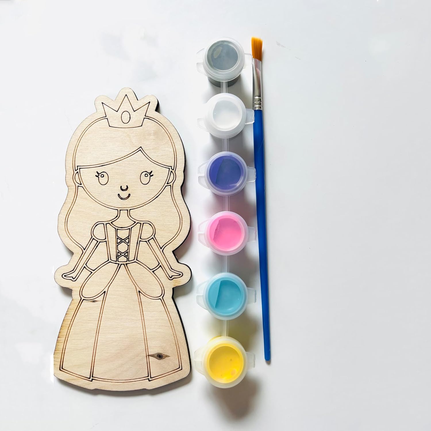 Wooden princess cutout with paint supplies on a white background