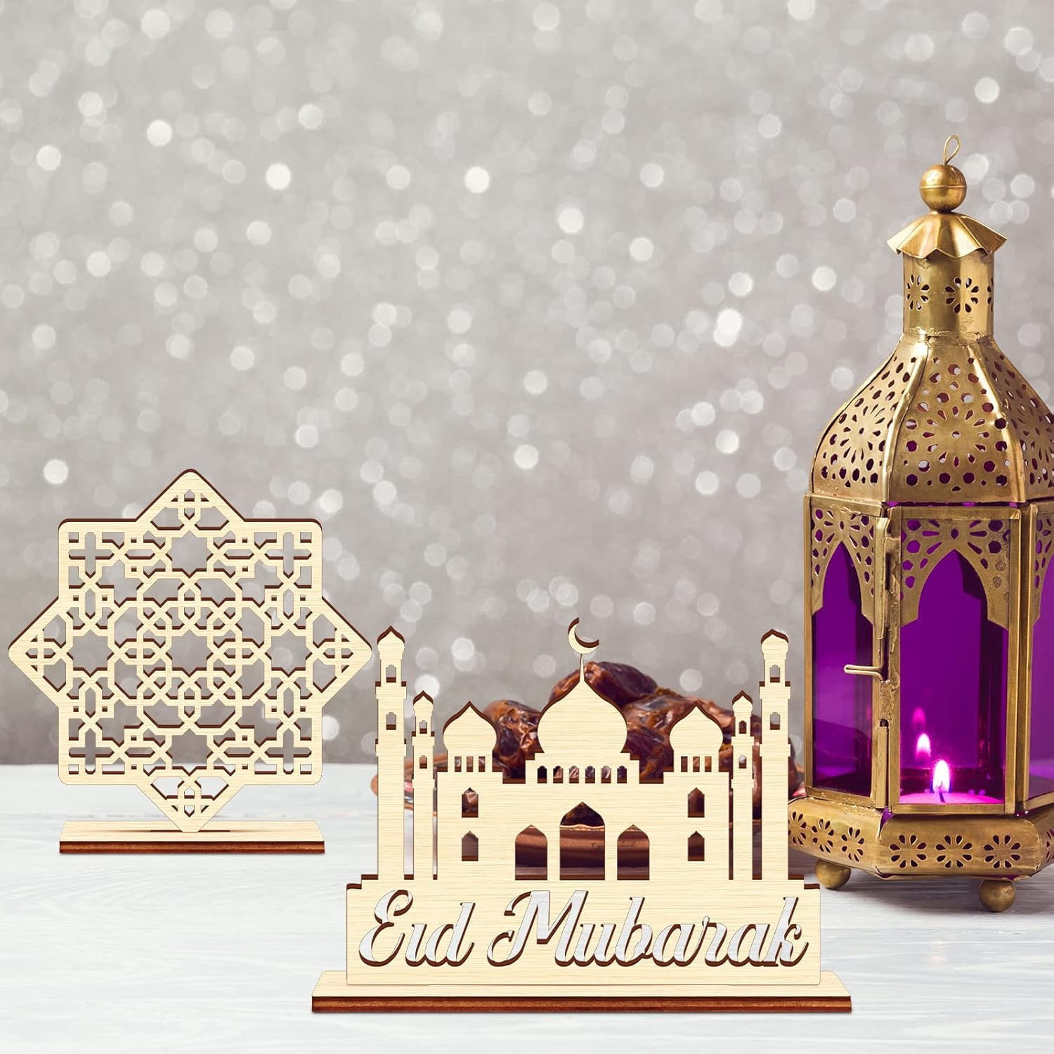 Decorative set with 'Eid Mubarak' card, miniature mosque model, and gold lantern on a gray background.