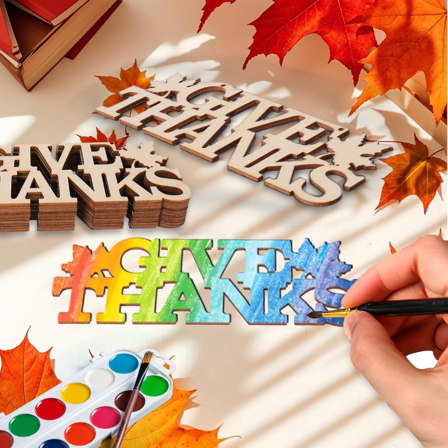 Wooden letters spelling 'THANKS' with a hand painting colorful letters on a white surface with autumn leaves.