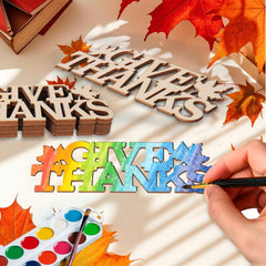 Wooden letters spelling 'THANKS' with a hand painting colorful letters on a white surface with autumn leaves.