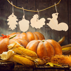 Decorative wooden cutouts of pumpkins, corn, and a squirrel on a rustic wooden surface with a blurred background.