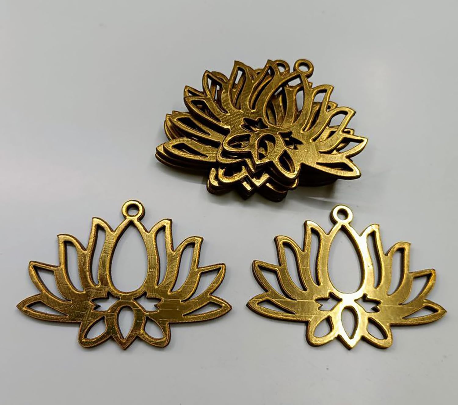 Three gold lotus flower pendants on a gray background