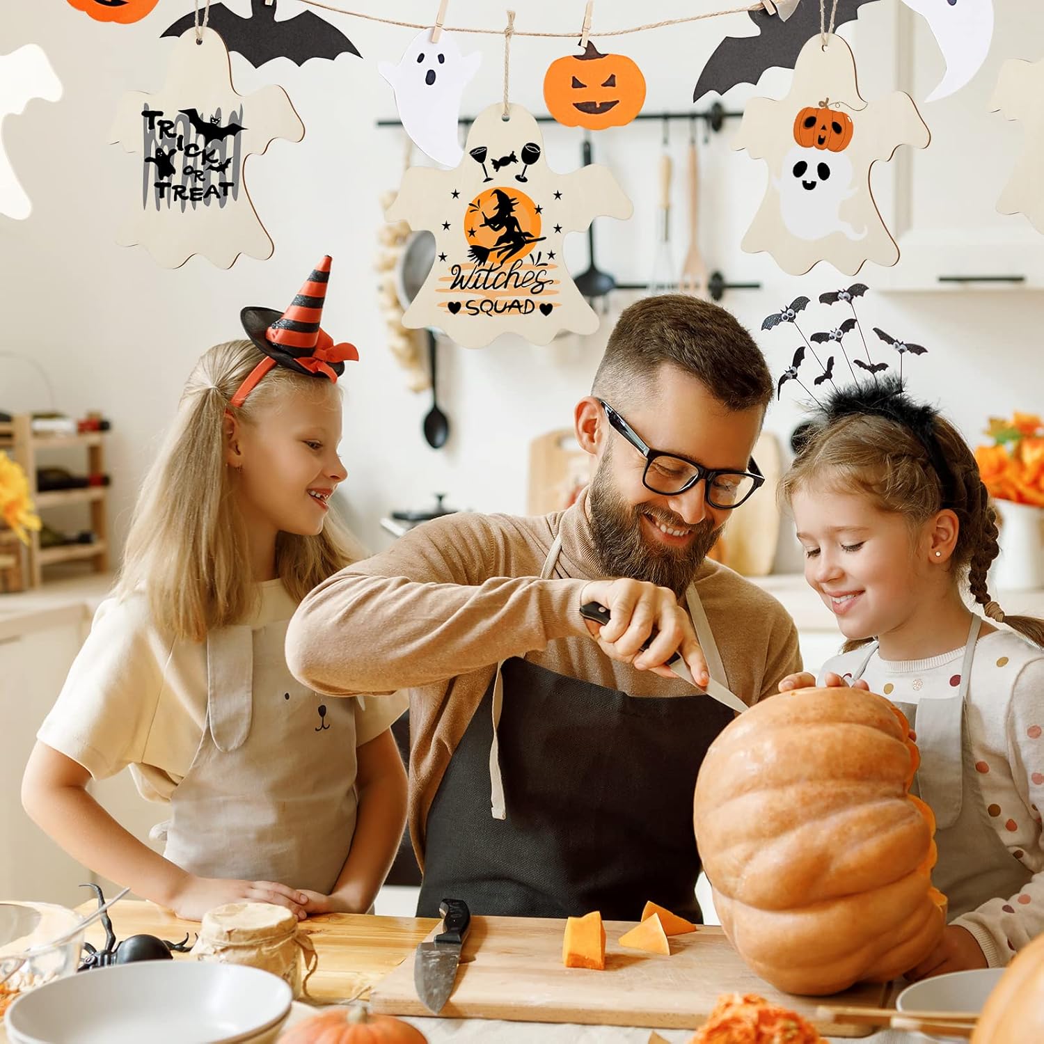 Man and two children carving a pumpkin with Halloween decorations in the background