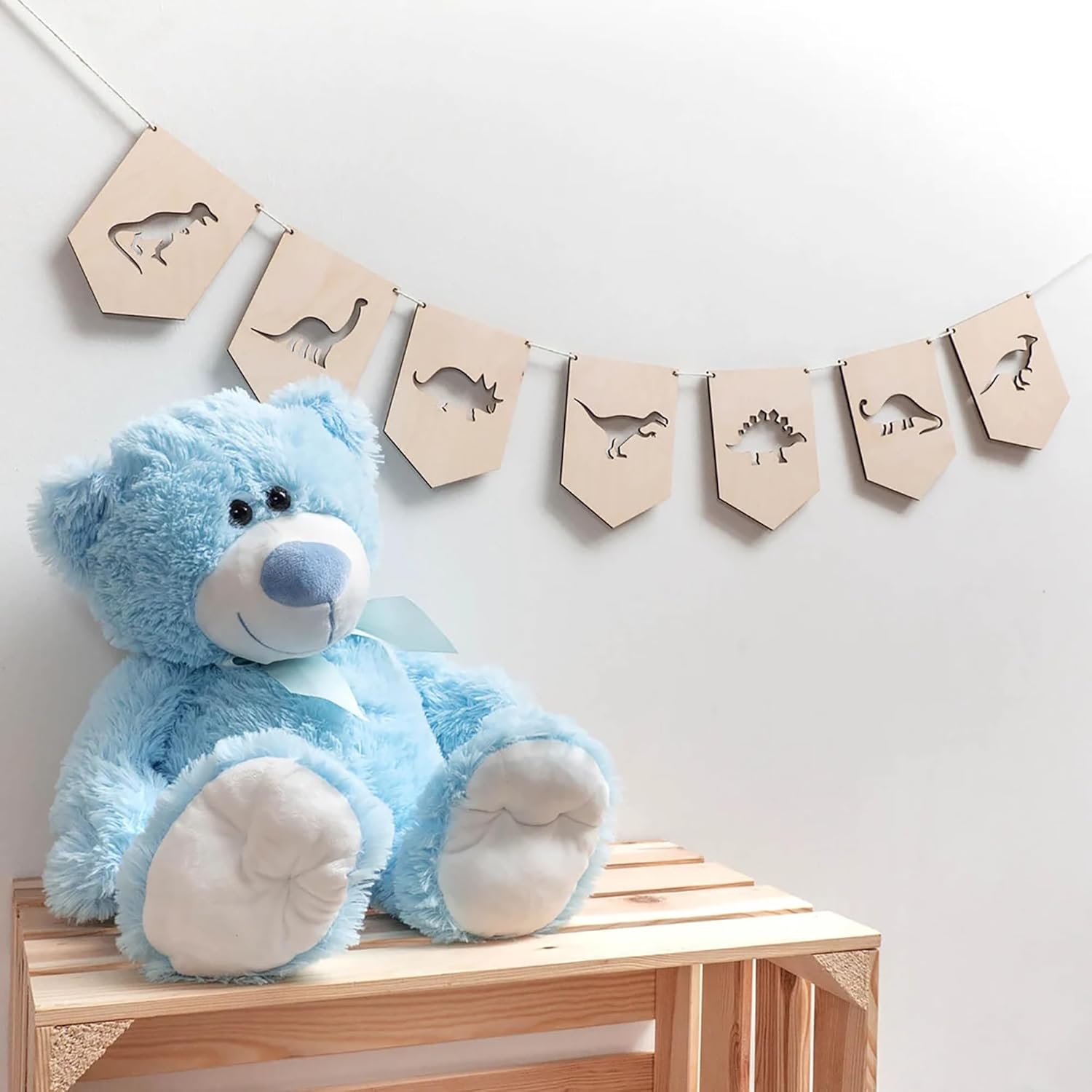 Blue teddy bear on a wooden bench with dinosaur-themed decor in the background