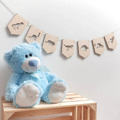 Blue teddy bear on a wooden bench with dinosaur-themed decor in the background