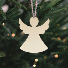 Wooden angel ornament hanging on a Christmas tree with blurred lights in the background