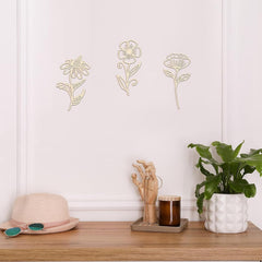 Decorative floral wall stickers on a white wall with a wooden shelf featuring a hat, plant, and candle.