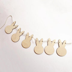 Wooden bunny shapes on a string against a light pink background