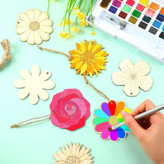 Colorful paper flowers and watercolor paint set on a light green background