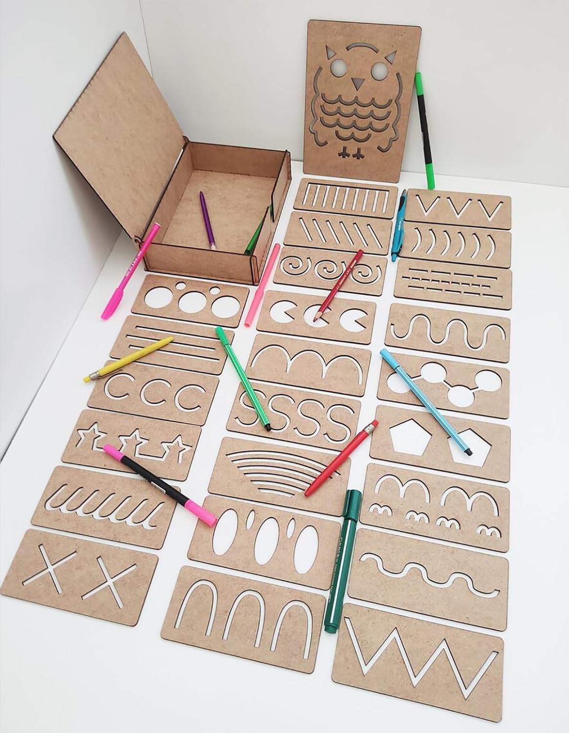 Cardboard stencils with various shapes and letters on a white surface with markers.