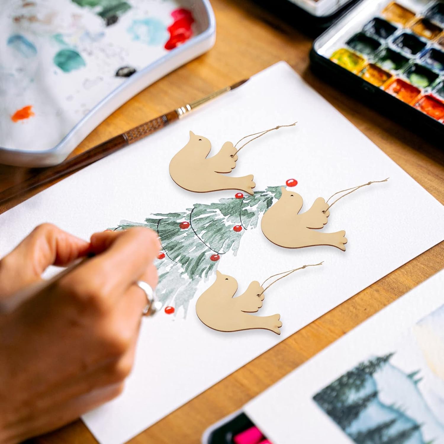 Hand painting wooden bird ornaments on a Christmas tree design with watercolor paints.