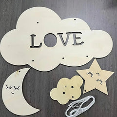 Decorative cloud with 'LOVE' letters, star, moon, and flower on a wooden surface.