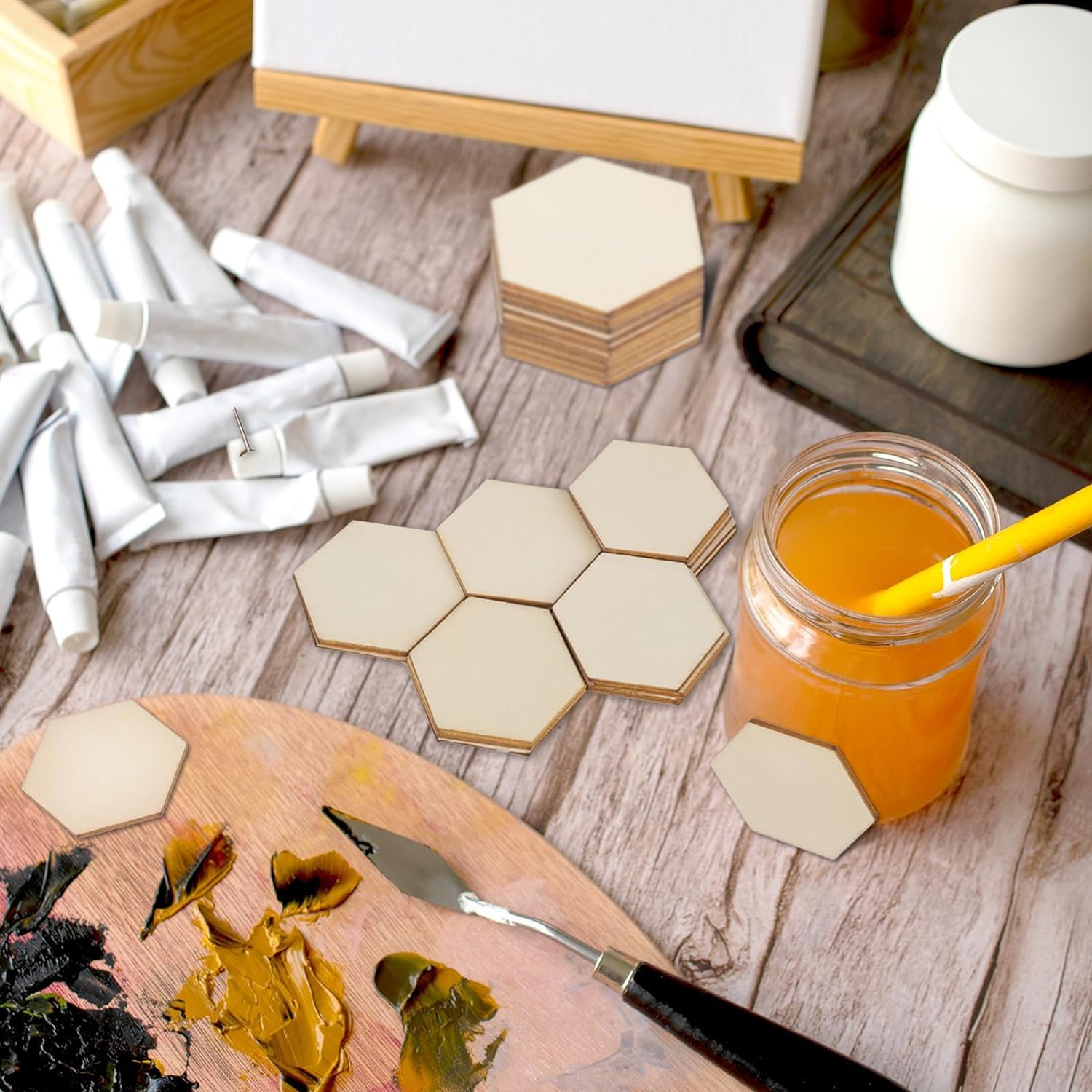 Hexagonal coasters on a wooden surface with art supplies and a drink.