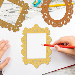 Decorative gold frames on a white surface with a hand holding a red pencil.