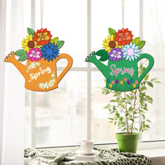 Two colorful watering can-shaped spring decorations with flowers on a windowsill.