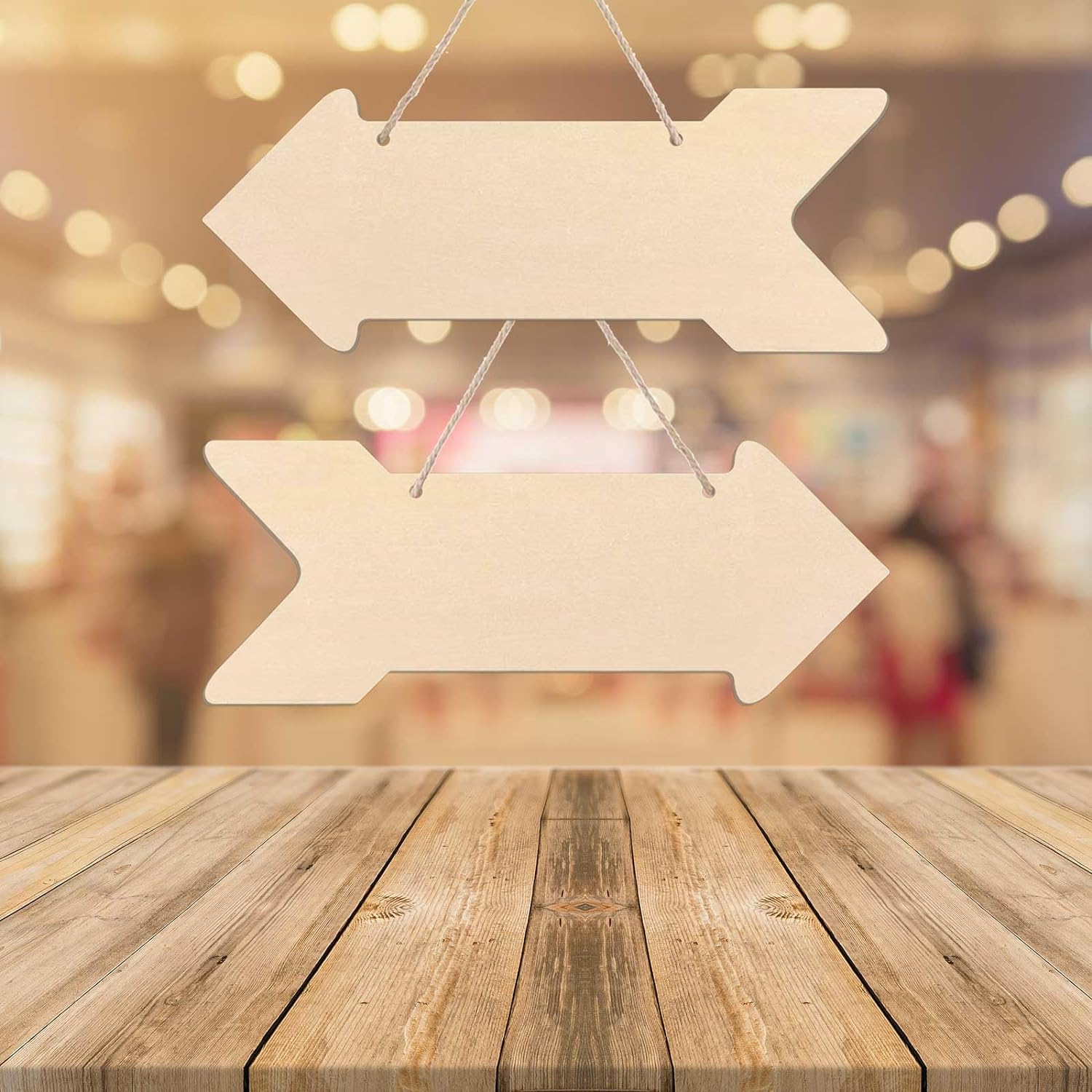 Two wooden arrow signs hanging above a wooden table with a blurred background