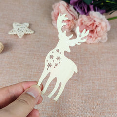 Decorative paper deer cutout held by a hand on a textured surface with flowers in the background