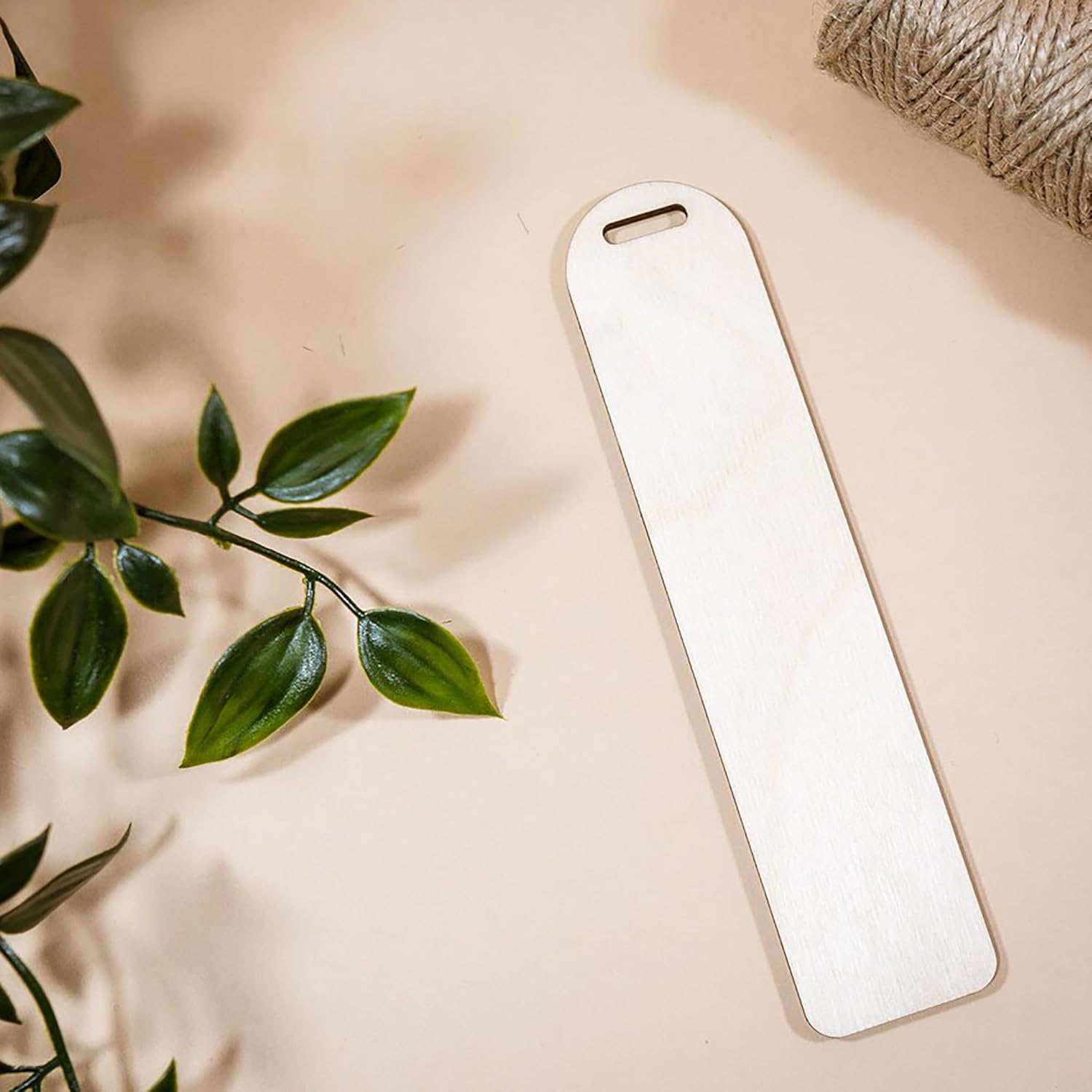 White rectangular object on a beige surface with green leaves and twine in the background