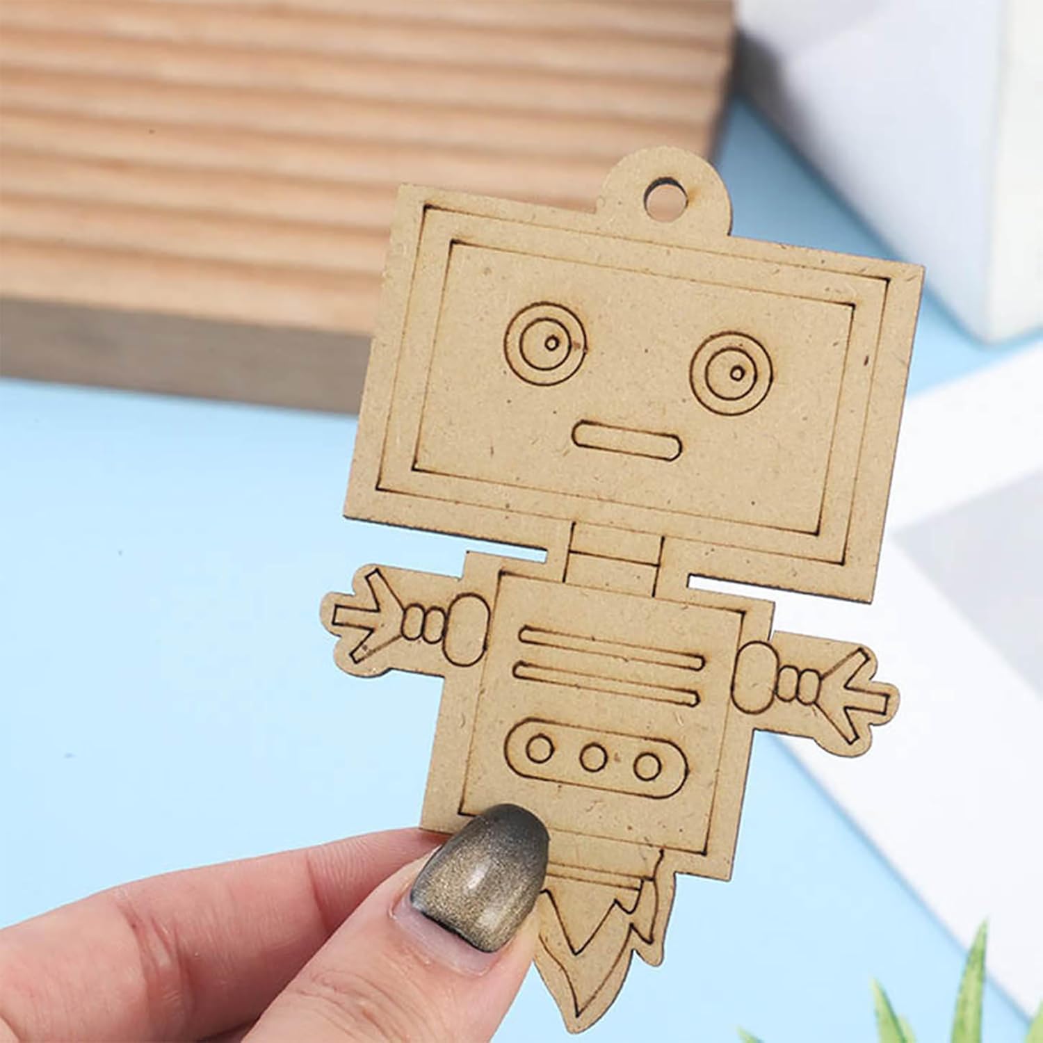 Cardboard robot cutout held by a hand on a light blue background