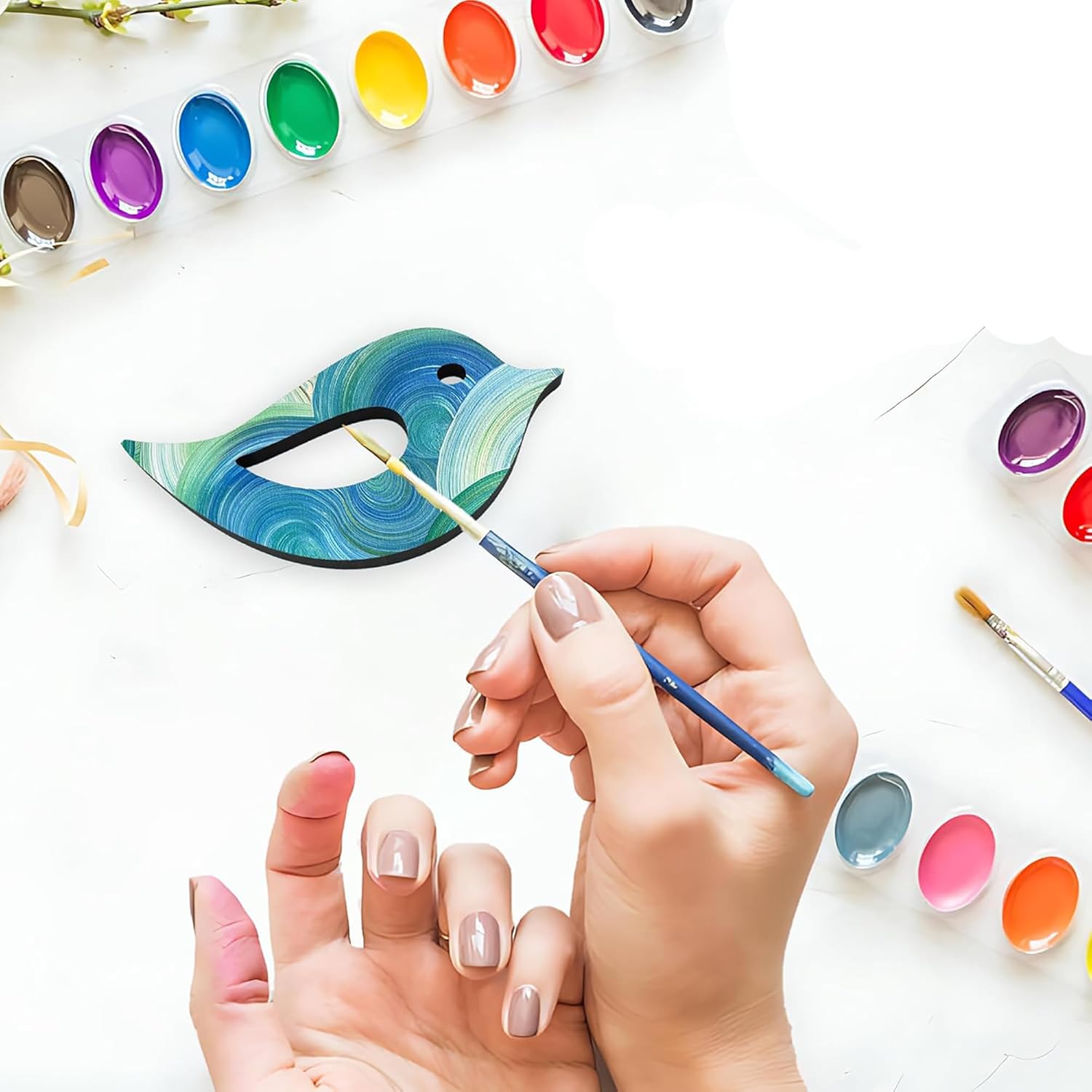 Person painting a ceramic fish with colorful glazes on a white surface