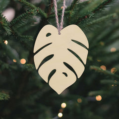 Heart-shaped leaf ornament hanging on a Christmas tree with blurred lights in the background