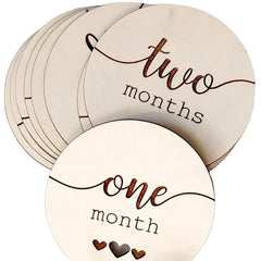 Round wooden discs with 'one month' and 'two months' text, used for baby milestone tracking.