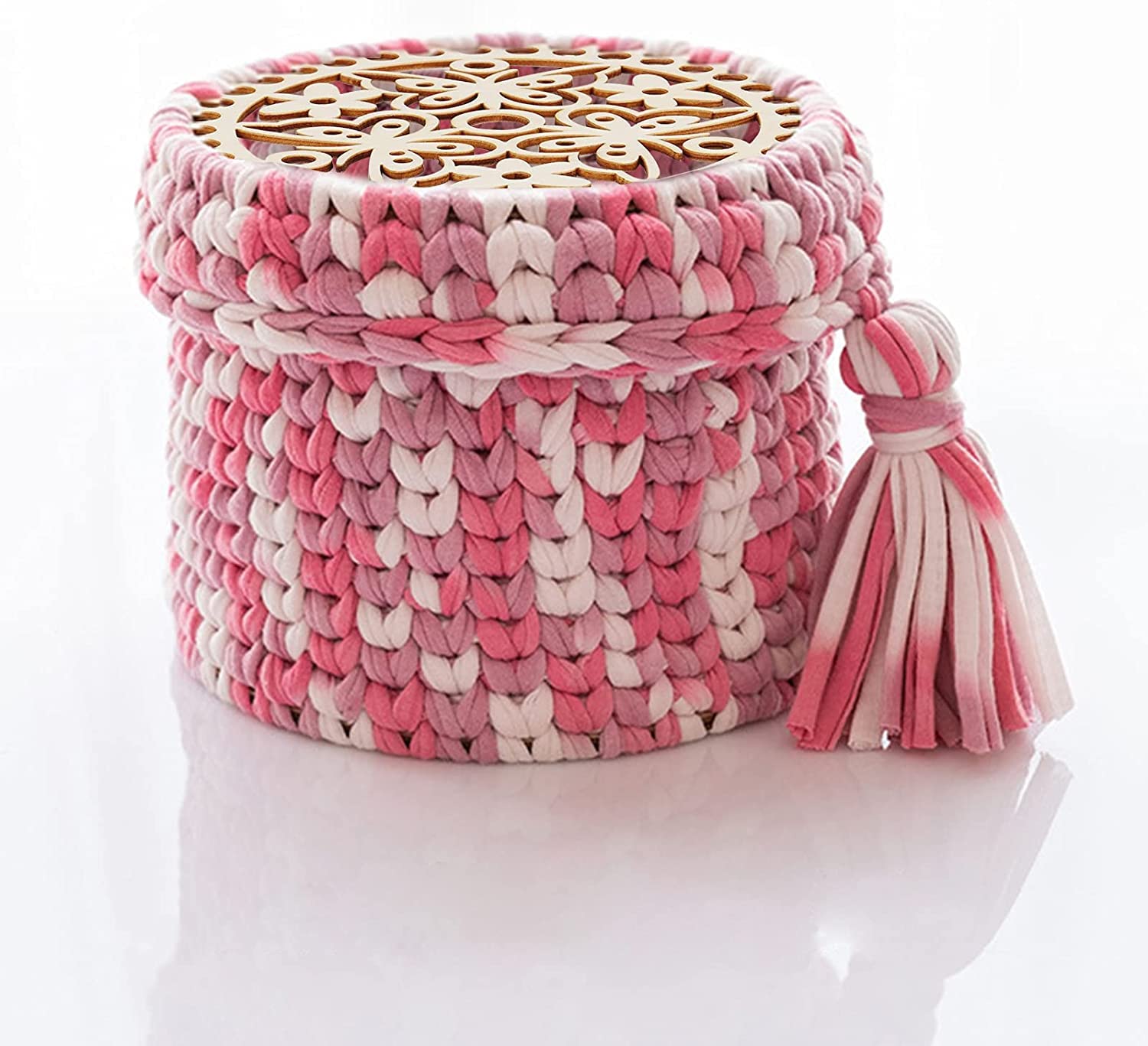 Pink and white woven basket with a tassel on a mannequin against a white background