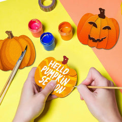 Person painting a circular pumpkin-shaped sign with 'Hello Pumpkin Season' text on a colorful background.