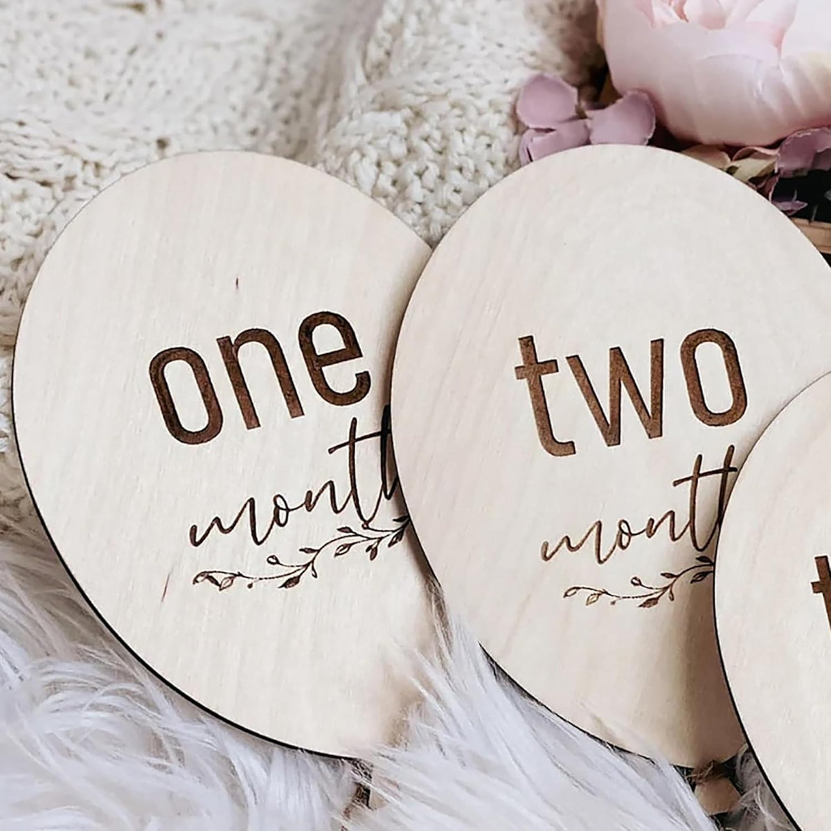 Wooden circular markers with 'one month' and 'two months' text on a soft surface.