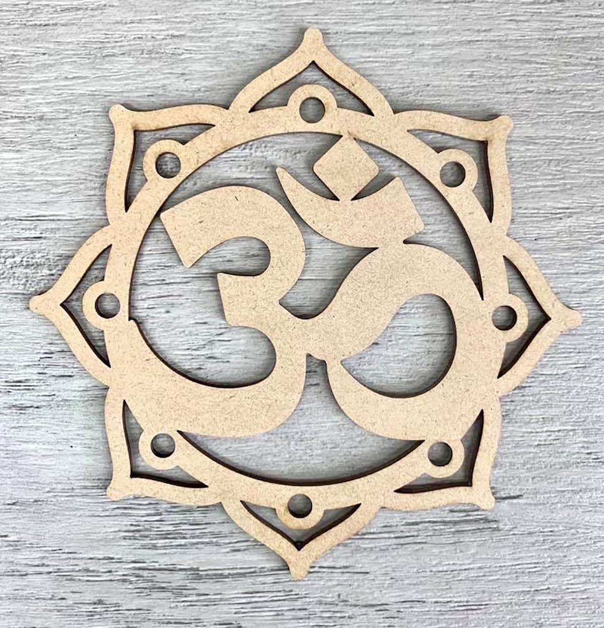 Decorative wooden piece with intricate cut-out design on a gray wooden surface