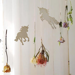 Decorative mobile with unicorn silhouettes and hanging flowers against a white background