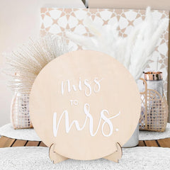 Round wooden sign with 'Miss to Mrs.' text on a decorative background