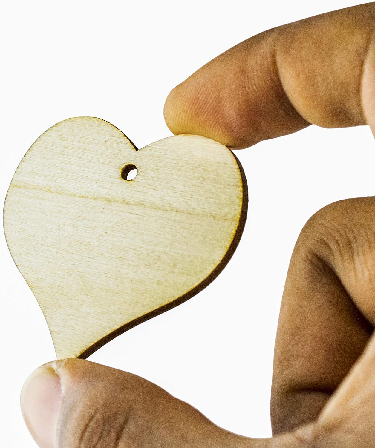 Hand holding a wooden heart-shaped object against a white background