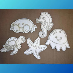 Set of white cut-out sea creature shapes on a brown background