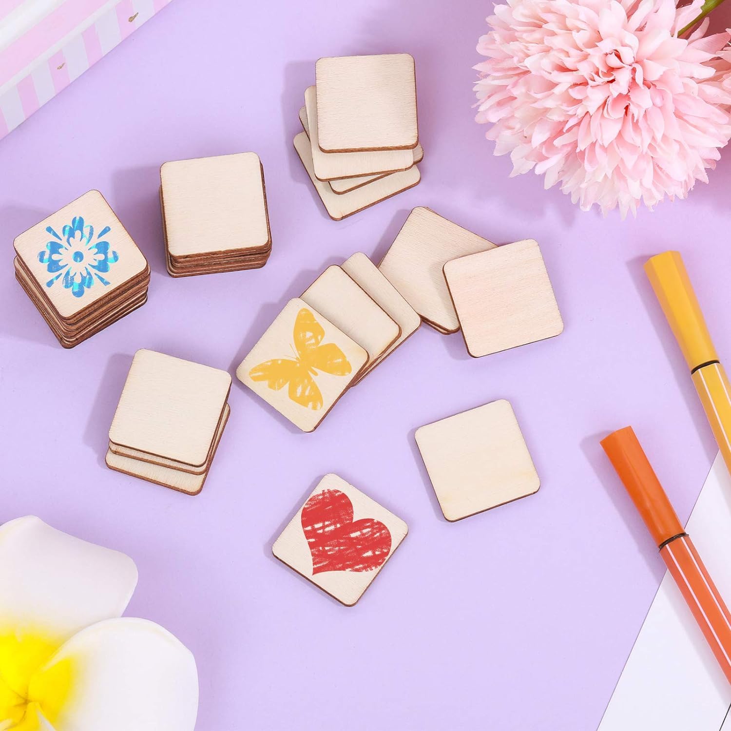Wooden square stamps with colorful designs on a purple background with flowers and pens.