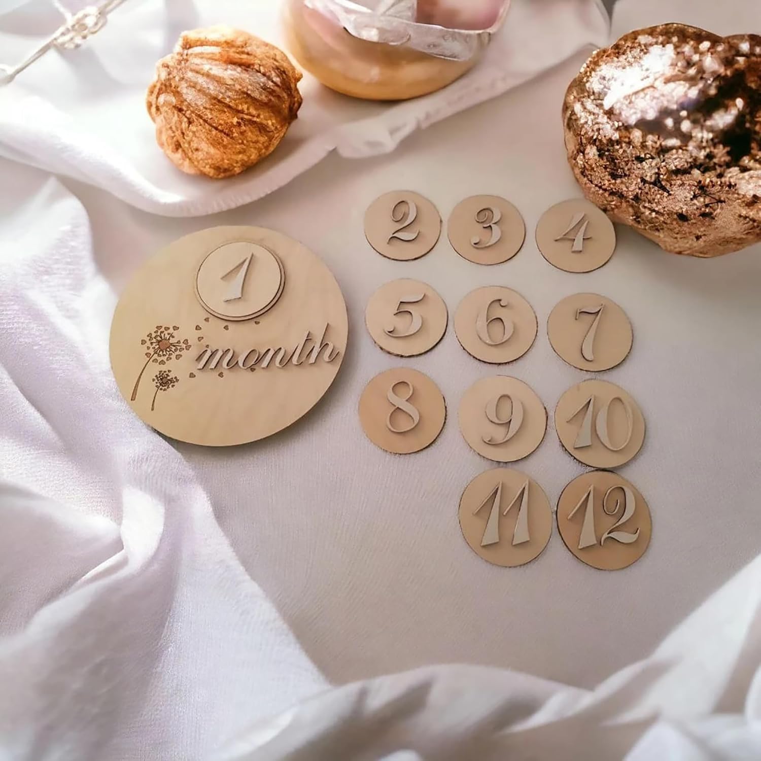 Wooden milestone discs with numbers on a soft fabric background