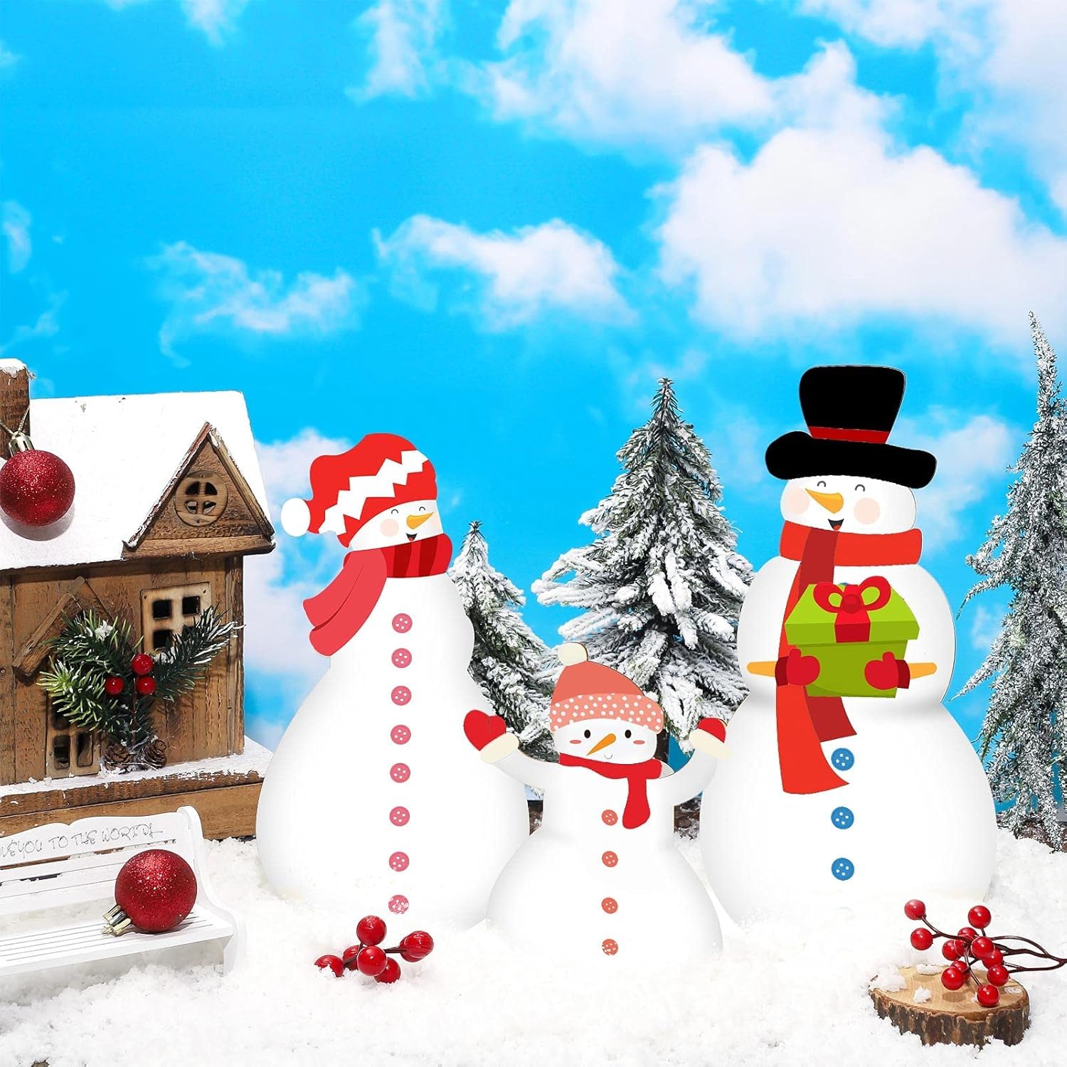 Three snowmen with festive accessories in a snowy landscape with a clear blue sky.