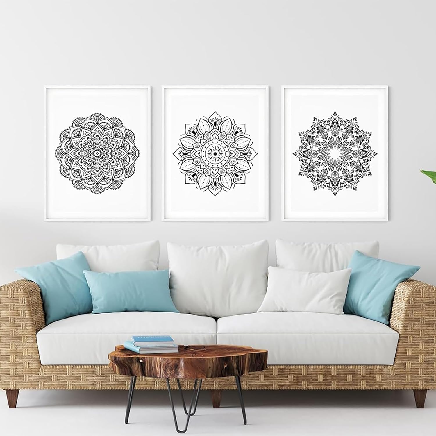 Three black and white mandala artworks on a wall above a white sofa with blue and white pillows.