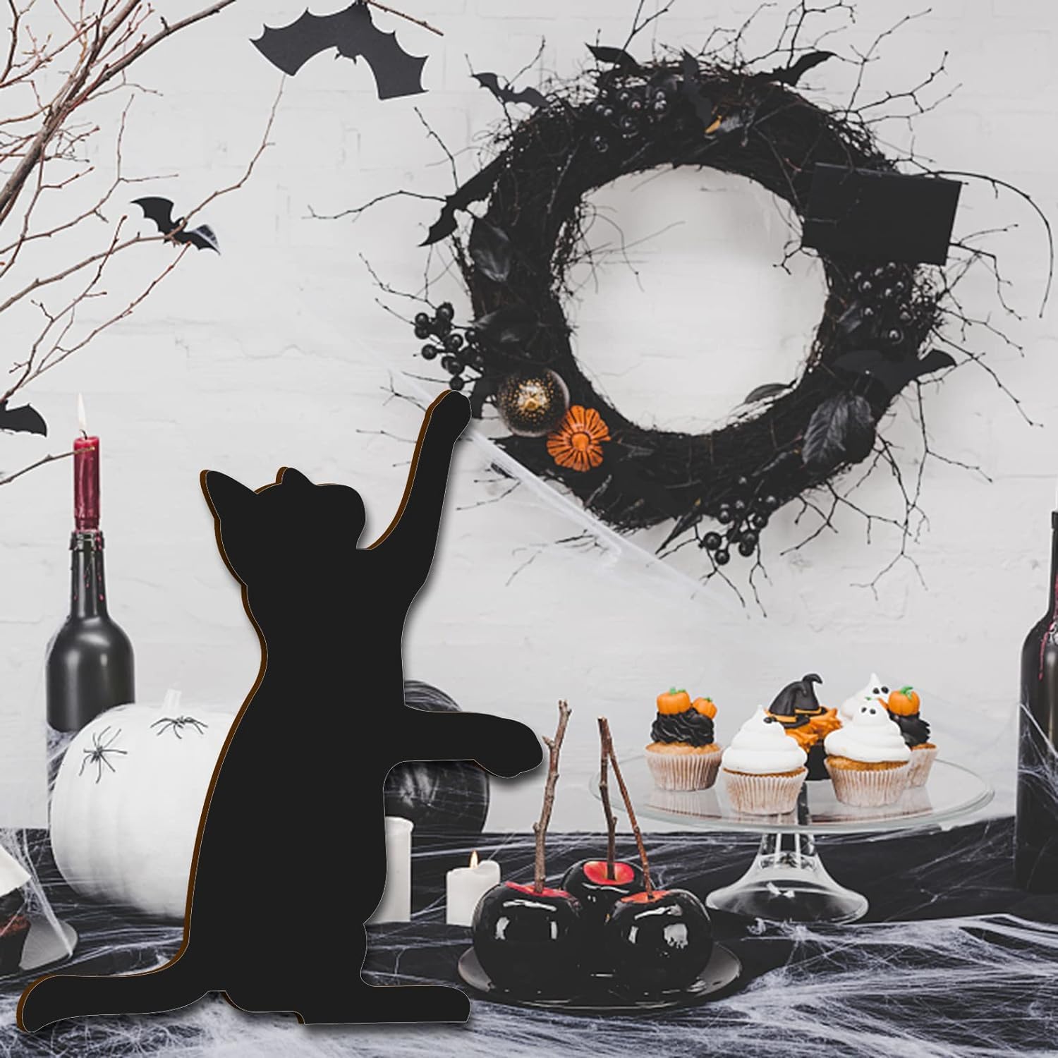 Halloween-themed setting with a black cat silhouette, wreath, and festive treats.