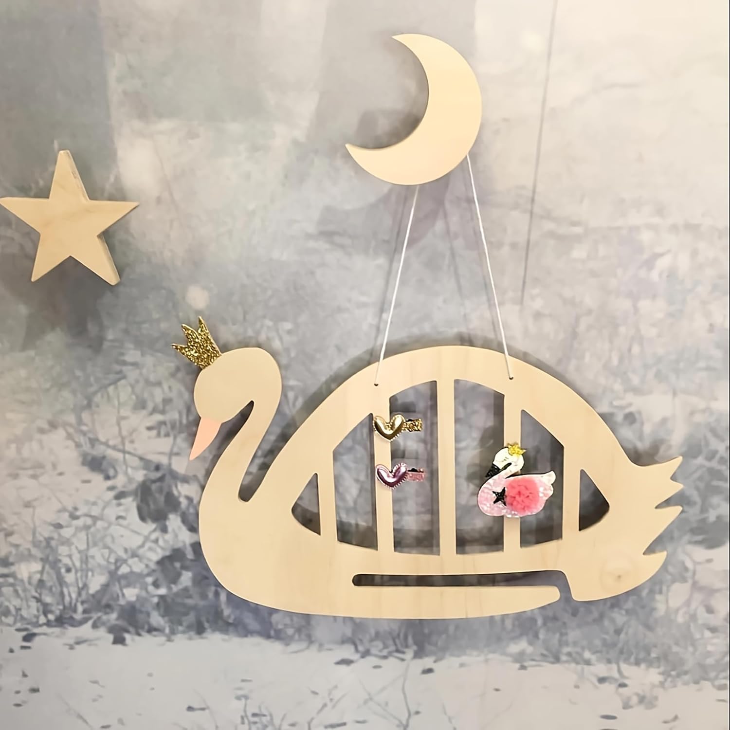 Wooden swan decoration with a crown, moon, and star on a textured wall.