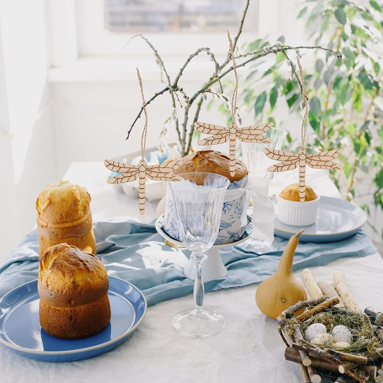 Decorative table setting with pastries, a glass, and natural elements on a light surface.