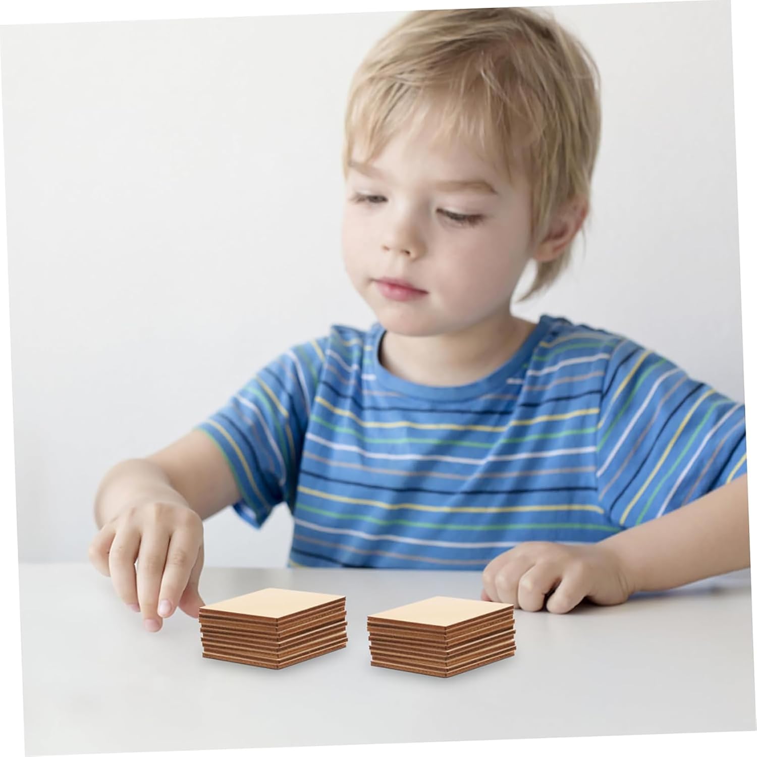 Child playing with wooden blocks on a white surface