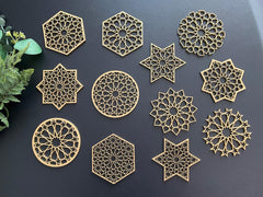 Gold geometric coasters on a dark surface with greenery