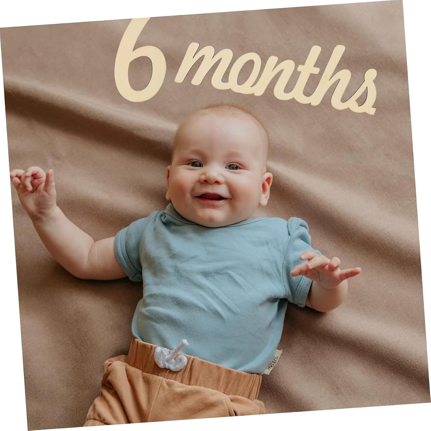 Baby lying on a brown blanket with '6 months' text